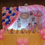 Pink and white 1st birthday stage decoration with balloon arch in Bangalore