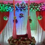 Traditional flower decoration setup with drapes and floral backdrop